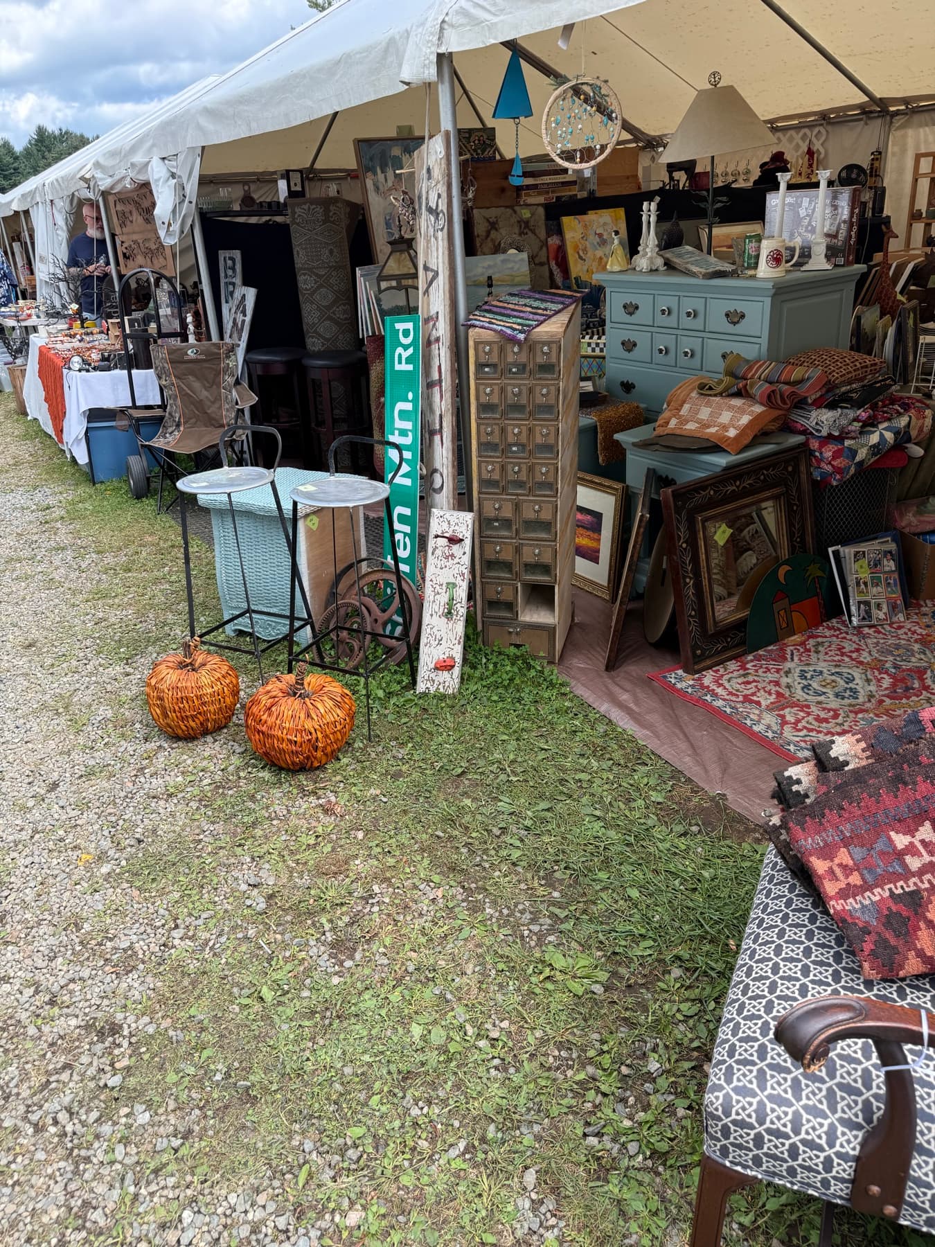 A styled fall vignette with a blue dresser, quilts, and woven pumpkins at a Brimfield booth