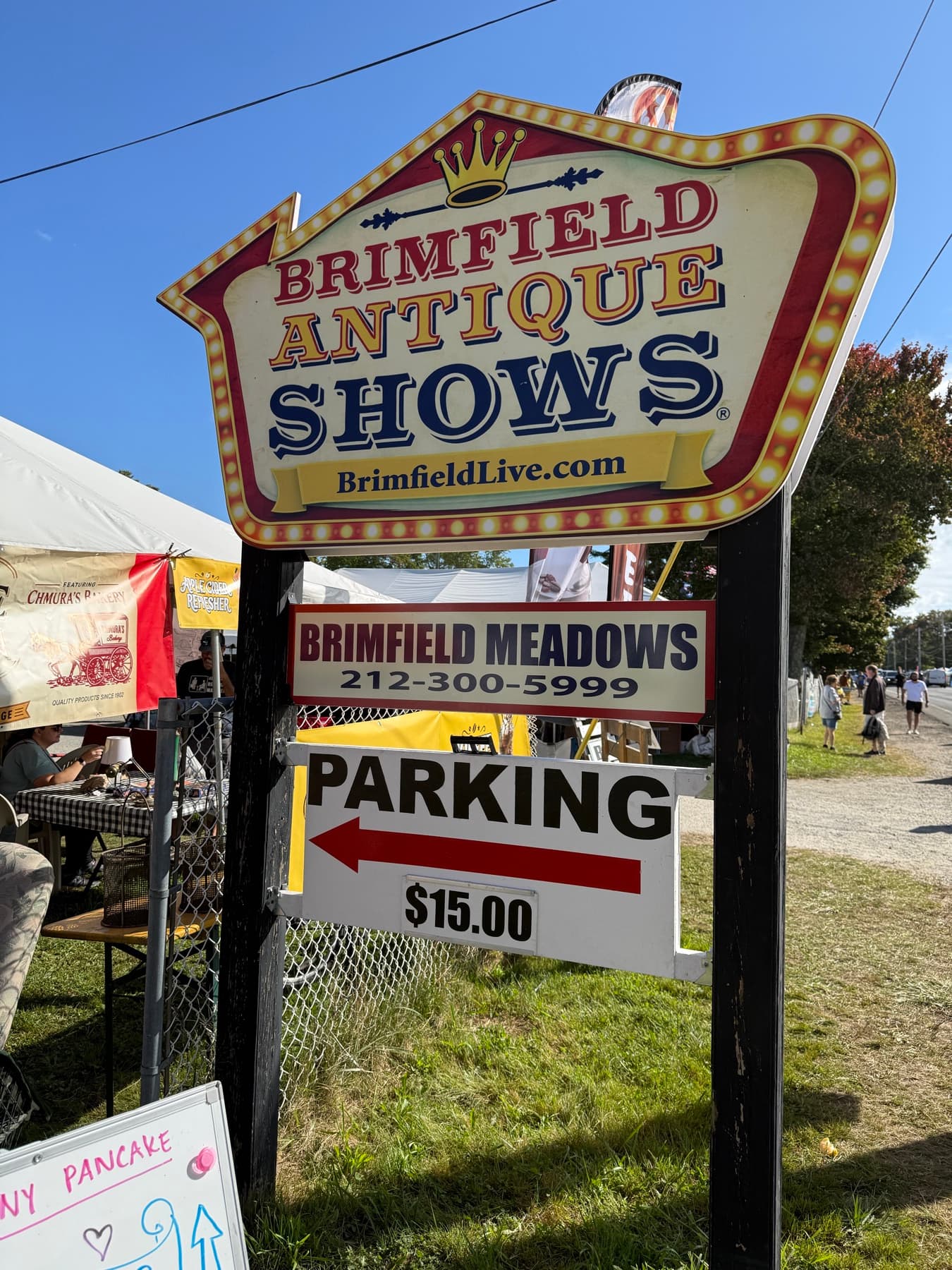 The official Brimfield Antique Shows sign for Brimfield Meadows, with a $15 parking sign underneath