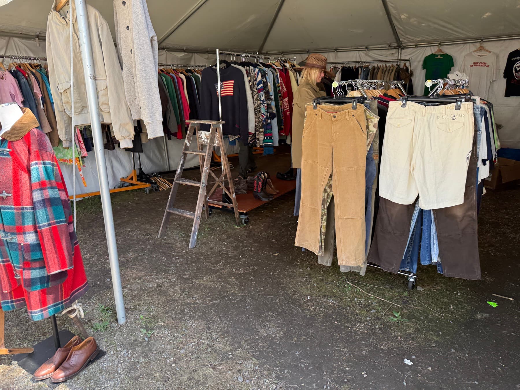 Racks of vintage clothing including corduroys and shorts at Brimfield