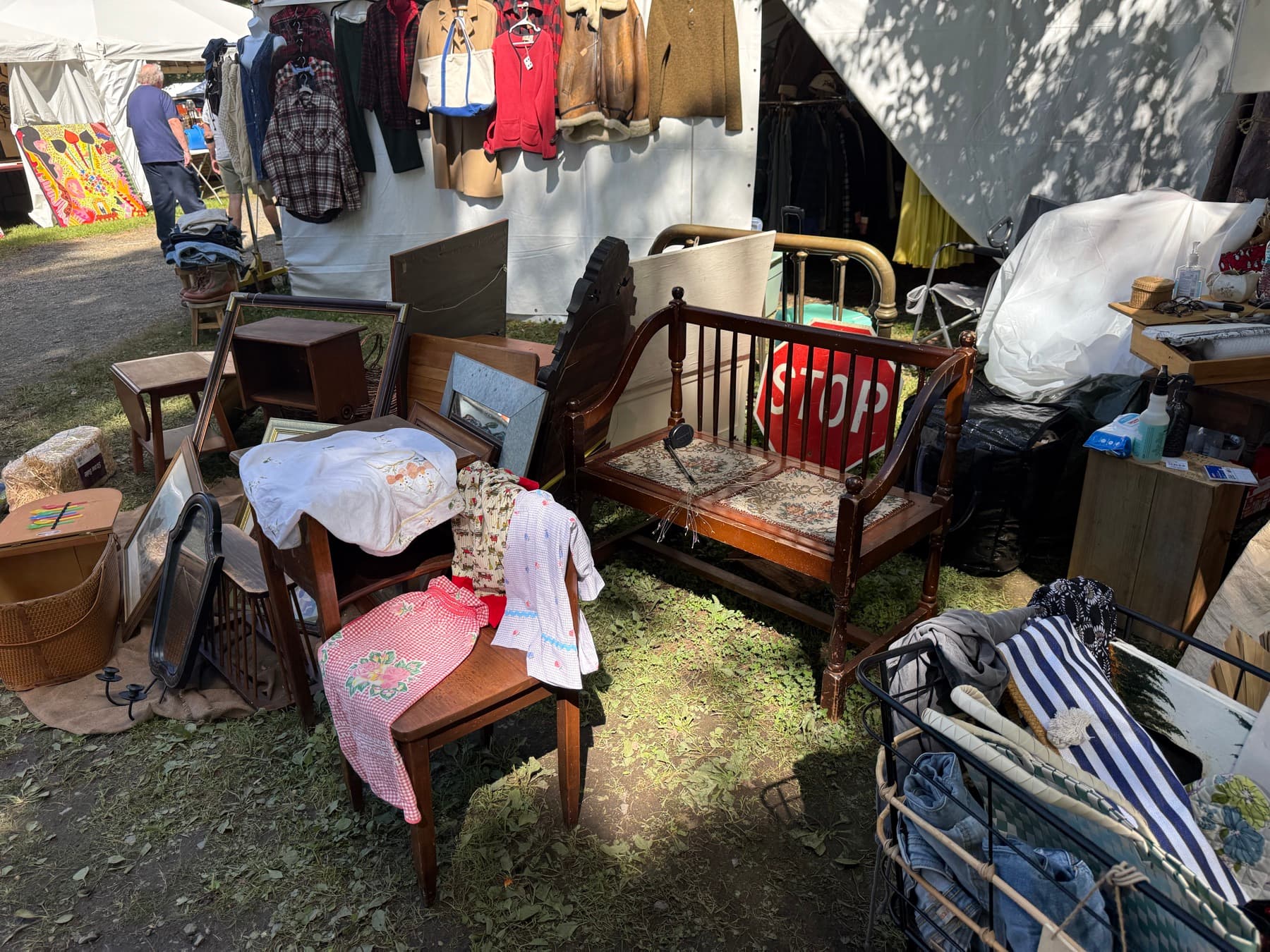 A pile of antique furniture and a vintage STOP sign at a Brimfield booth