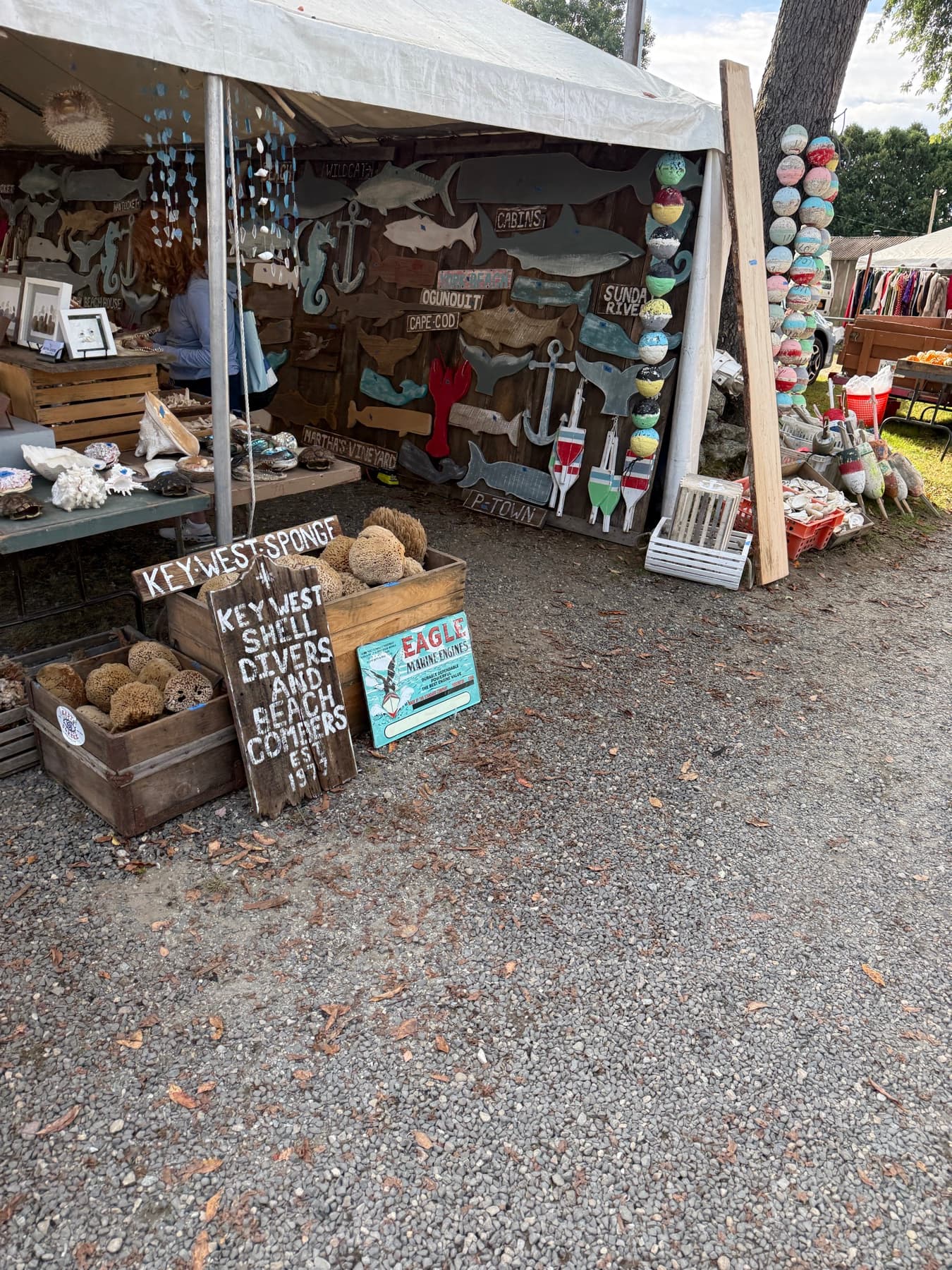 A nautical-themed booth with wooden fish cutouts, buoys, and shells at Brimfield
